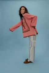 Buzo oversized de punto color tostado con diseño gráfico frontal en azul inspirado en una estampilla con una sirena y el texto 'Taormina'. Presenta tajos laterales, cuello redondo y terminaciones en contraste de color azul.