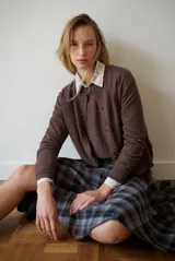 Cardigan de punto color marrón, con escote redondo y cierre frontal de botones.