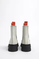 Botín Chelsea de cuero color rosa con puntera y suela track color negro. Cuenta con elásticos laterales negros y tiradores en la parte trasera.