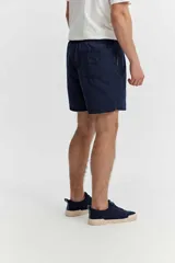 Short de baño azul, de corte clásico y largo corto, con cintura elástica y cordón ajustable bicolor. Cuenta con bolsillos laterales y uno trasero.