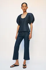 Blusa de Zara confeccionada en mezcla de algodón con acabado denim. Presenta escote redondo, mangas cortas abullonadas con volumen y costuras con pespuntes a contraste. Cierre posterior con cremallera oculta.