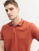 Remera polo azul marino con ribetes blancos en el cuello y en los bordes de las mangas corta, y cierre frontal de botones.