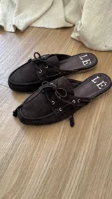 Mules de gamuza color tostado con diseño de zapato náutico, con cordones frontales y plantilla con logo estampado.