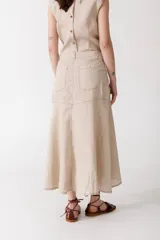 Falda midi de lino color beige, de corte evasé con bolsillos delanteros, cierre de botón y trabillas para cinto.