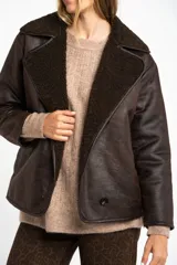 Campera tipo gamulan de corte oversize, color marrón oscuro con interior y solapas de corderito al tono. Presenta cierre frontal y mangas largas.