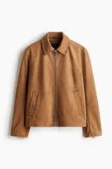 Campera de gamuza color camel, con cuello camisero, cierre frontal y bolsillos laterales con cierre. Presenta un corte estándar y forro interior.