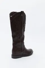 Bota de caña alta estilo western confeccionada en cuero sintético, con bordados decorativos en relieve a lo largo de la caña y puntera afinada.