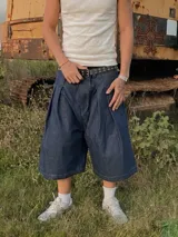 Bermuda de jean estilo raw denim, confeccionada en algodón de 12 onzas. Presenta un parche de cuero grabado con diseño barroco en la parte posterior y costuras reforzadas en contraste.