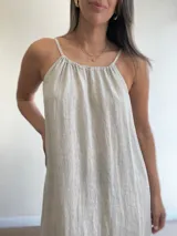 Vestido largo de lino color negro oscuro, con escote fruncido y tirantes finos ajustables. Presenta aberturas laterales en el ruedo.