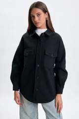 Sobrecamisa de paño en color negro, con cuello clásico, cierre frontal de botones y bolsillos frontales con solapa.