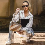 Sobre de mano de símil cuero con diseño de franjas diagonales en negro, blanco y marrón. Cuenta con cierre metálico frontal, bolsillo interior con cierre y otro abierto con división. Incluye correa desmontable para usar como bandolera.