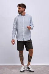 Camisa de manga larga para hombre, con cuello clásico y botones frontales. Presenta un estampado de rayas verticales finas en tonos azul claro y blanco.