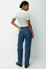 Jean de tiro alto confeccionado en denim rígido, con diseño de cinco bolsillos, cierre con botón y corte de pierna recta levemente holgado.