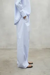 Pantalon de corte relajado y tiro alto, confeccionado en algodon, con pliegues frontales y bolsillos laterales.