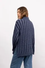 Sweater de tejido de punto con diseño de trenzas verticales, cuello alto, manga larga y silueta oversize de largo extendido.