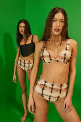 Conjunto de bikini de dos piezas confeccionado en lycra brillante con estampado tie-dye en tonos naranja, negro y blanco. El corpiño es de estilo triángulo con breteles anchos fijos y pinzas para mayor volumen. La bombacha es de tiro medio con cobertura clásica.