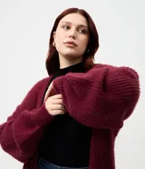 Cardigan abierto de punto pesado con textura peludita, manga larga y diseño alargado. Prenda versátil de corte holgado.
