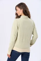 Buzo tejido combinado de color beige, con cuello alto, medio cierre metálico y puños y ruedo acanalados en tono tostado.