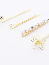 Set de cuatro horquillas doradas con distintos diseños: una con strass, una con perla, una con hilera de perlas y strass, y una con dije de flor calada.