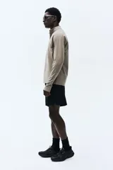 Short deportivo negro de corte estándar, confeccionado en tejido funcional DryMove™ que absorbe el sudor. Presenta cintura elástica con cordón de ajuste, bolsillos al bies, un bolsillo lateral con cierre y aberturas cortas en el bajo.