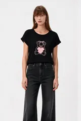 Remera negra de algodón con cuello a la base, mangas cortas con vuelta y estampado frontal de oso con corazón en tonos rosados.