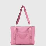Bolso tipo tote de gran capacidad, color rosado, con diseño funcional y deportivo. Cuenta con doble asa de mano y una correa larga ajustable con el logo de la marca estampado. Incluye compartimento interno para laptop y bolsillo trasero adaptable para maletas.