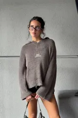 Sweater de textura suave y afelpada en color gris oscuro, con diseño de cuello redondo y mangas largas. Presenta un estampado gráfico en color blanco en la espalda con la inscripción 'odd studios'.