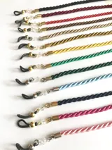 Cordón para sujetar lentes, disponible en varios colores: negro, bordó, rojo, marrón, dorado, amarillo, verde, celeste, azul, fucsia y rosa. Cuenta con terminales de goma para sujetar las patillas de los lentes y detalles de cuentas de cristal.