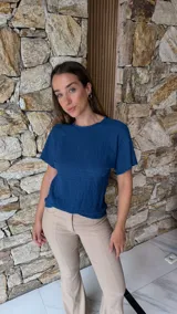 Blusa de manga corta color azul oscuro con textura arrugada o plisada, cuello redondo con borde festoneado.