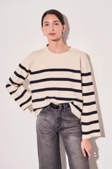 Sweater de punto con diseño a rayas horizontales en color crema y negro, de cuello redondo y mangas largas con corte ligeramente acampanado.
