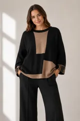 Buzo de punto de corte holgado con diseño de bloques de color en negro y beige. Presenta cuello redondo, mangas largas con puños decorados con lentejuelas y terminaciones acanaladas.