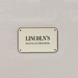 Billetera larga con cierre perimetral, confeccionada en material sintético texturizado color mostaza. Cuenta con correa de mano extraíble y placa metálica con logo de la marca en el frente.