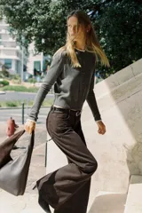 Chaqueta de punto color beige, de manga larga y corte corto, con cuello redondo y puños terminados en puntilla blanca a contraste.