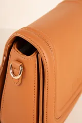 Bandolera negra de cuero sintético con correa de tela desmontable y regulable. Cuenta con un compartimento interno y dos bolsillos adicionales.