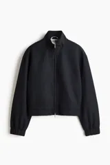 Campera bomber negra con cuello elevado, cierre frontal bidireccional y bolsillos laterales discretos. Cuenta con puños y dobladillo elásticos.