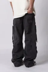 Jean de corte baggy con múltiples bolsillos cargo frontales con cierre metálico, tiro medio y tiras de ajuste en la botamanga.