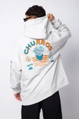 Buzo canguro gris claro de corte oversize, con capucha y cordones negros con letras blancas. Presenta un bolsillo tipo canguro y un estampado pequeño en el pecho y otro en la manga.