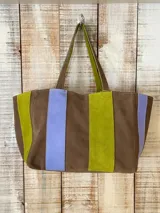 Cartera de cuero tipo tote bag, con diseño en bloques de color marrón, verde lima y lila, doble asa de hombro y cierre superior.