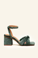 Sandalia de tacón cuadrado medio, confeccionada en terciopelo color verde. Presenta un diseño de tiras cruzadas con nudo en la parte frontal y una tira ajustable con hebilla metálica en el tobillo.