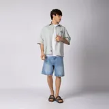 Camisa de manga corta color marfil, corte boxy, con cuello camisero, cierre frontal de botones y pequeño bordado marrón en el pecho con las siglas VCP.