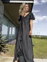 Vestido largo de lurex negro con acabado brillante, escote en V, mangas cortas con volados y falda con tajo lateral que revela un forro interior.