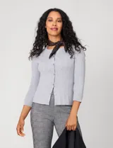 Cardigan blanco de tejido liviano con trama en relieve, cuello a la base y cierre frontal con botones a tono. Presenta mangas tres cuartos.