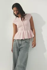 Saco ajustado en punto fino suave, color rosado, con cuello redondo, manga corta, hilera de botones al frente y peplum acampanado.