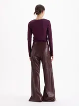 Pantalon de tiro alto y silueta wide leg, confeccionado en cuero. Presenta recortes frontales y laterales que estructuran la prenda y tajos en el ruedo que aportan movimiento.