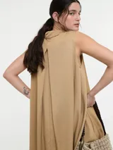 Vestido camisero corto color beige, sin mangas, con cuello clásico, cierre frontal con botones y bolsillos laterales.