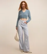 Cardigan cropped de punto color rosa claro, con textura de pelito, cuello en V, mangas largas, cierre frontal con botones y bolsillos delanteros.