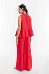 Pantalón de lino rojo con estampado de lunares plateados, cintura elástica, bolsillos laterales y piernas anchas.