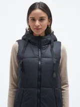 Chaleco largo acolchado color negro con capucha y cierre frontal.