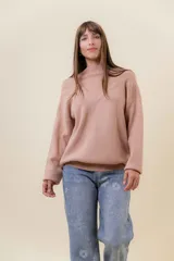 Sweater tejido de punto color blanco, con cuello alto y diseño en relieve tipo chevron en la parte frontal. Presenta un calce holgado con terminaciones acanaladas en puños y ruedo.