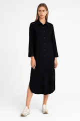 Túnica de lino con cuello camisero, cierre frontal con botones, manga larga y bolsillo en el pecho. Presenta un corte holgado y aberturas laterales en el ruedo.